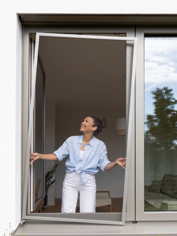 Frau hängt ganz einfach Fliegengitter in Fenster ein - ohne Bohren.