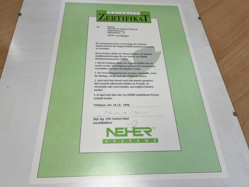 Neher Zertifikat auf grünem Hintergrund, ausgestellt für die Firma Schulz-Dobrick, mit Datum vom 19.12.1994.
