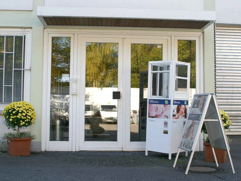 Eingangsbereich von RSD Systeme mit Ausstellungsstück für Insektenschutzfenster und Infotafel vor der Tür.
