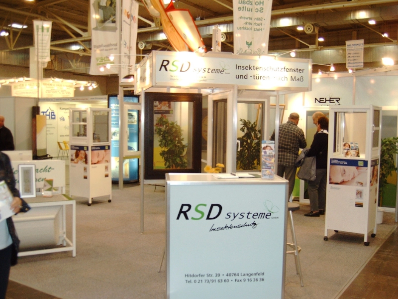 Messestand von RSD Systeme, der Insektenschutzfenster und -türen nach Maß präsentiert, mit Besuchern im Gespräch.