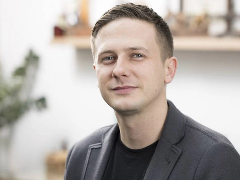 Porträt von Roman Schulz von Schulz Dobrick, mit neutralem Hintergrund und leichtem Lächeln.
